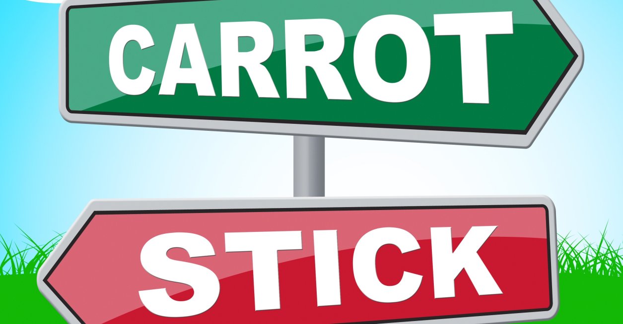 Two directional signs: one that reads "carrot" another that reads: "stick."